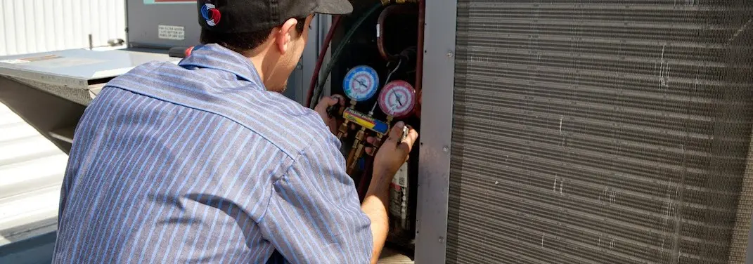 HVAC technician servicing a condenser unit in St. Augustine Beach
